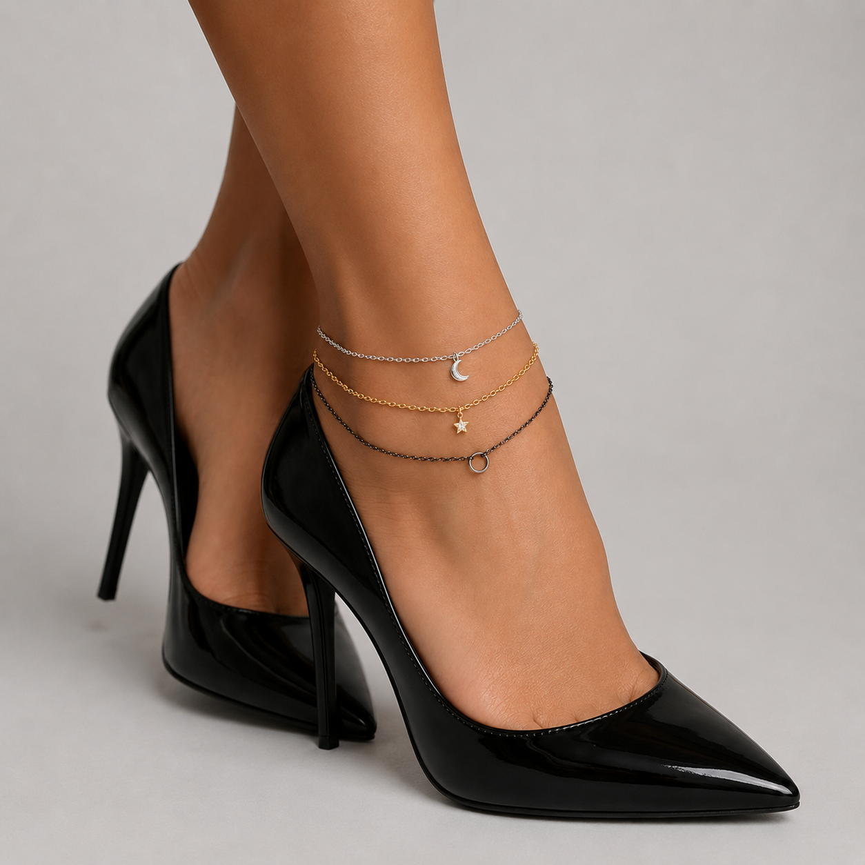 Mixed metal layered anklet - silver, gold and gunmetal chains with moon, star and O-ring charms on an ankle with black heels