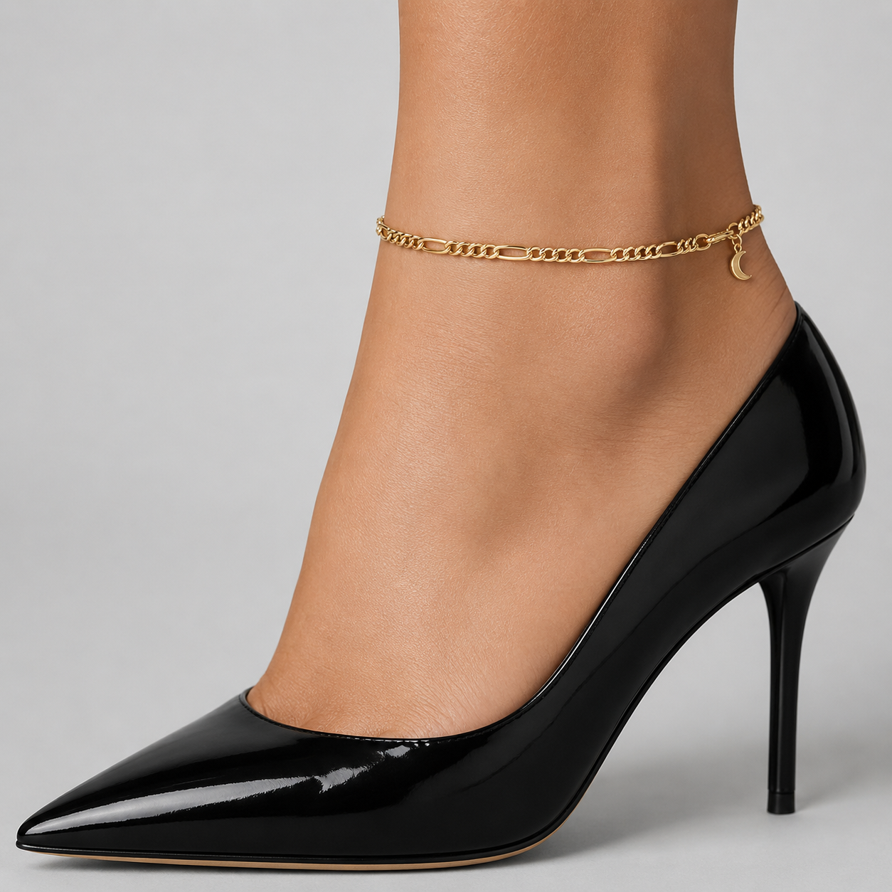 Gold figaro chain anklet - classic figaro links with a crescent moon charm, close-up on the ankle