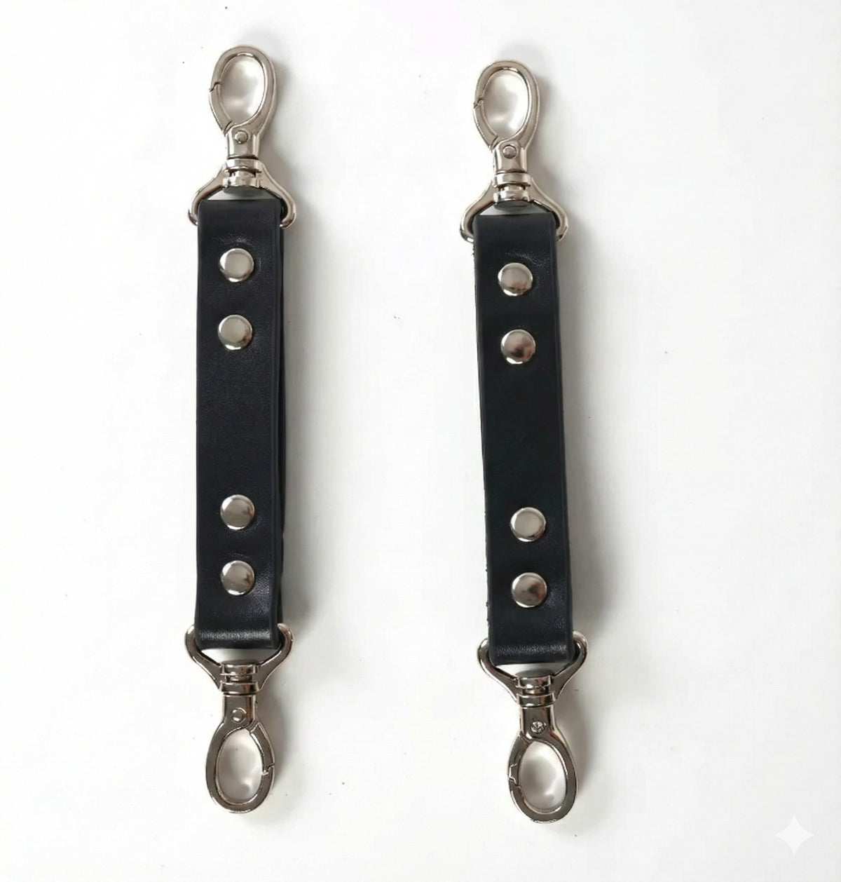 Pair of black faux leather harness extender straps with rivets and silver-tone snap hooks