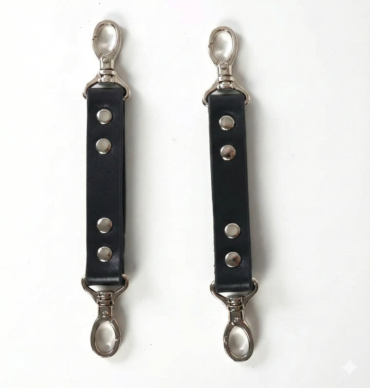 Pair of black faux leather harness extender straps with rivets and silver-tone snap hooks