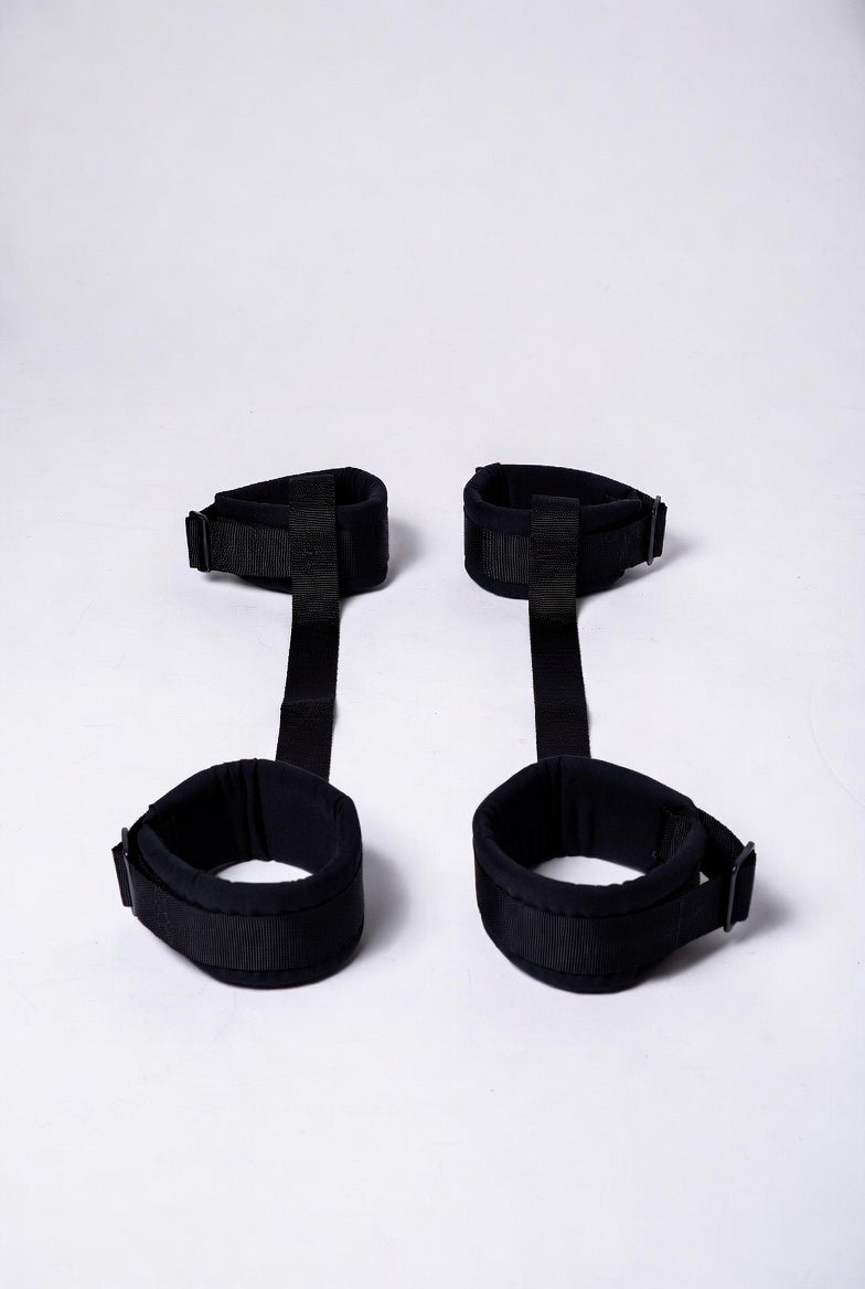 Under-bed restraint system with adjustable straps and padded cuffs