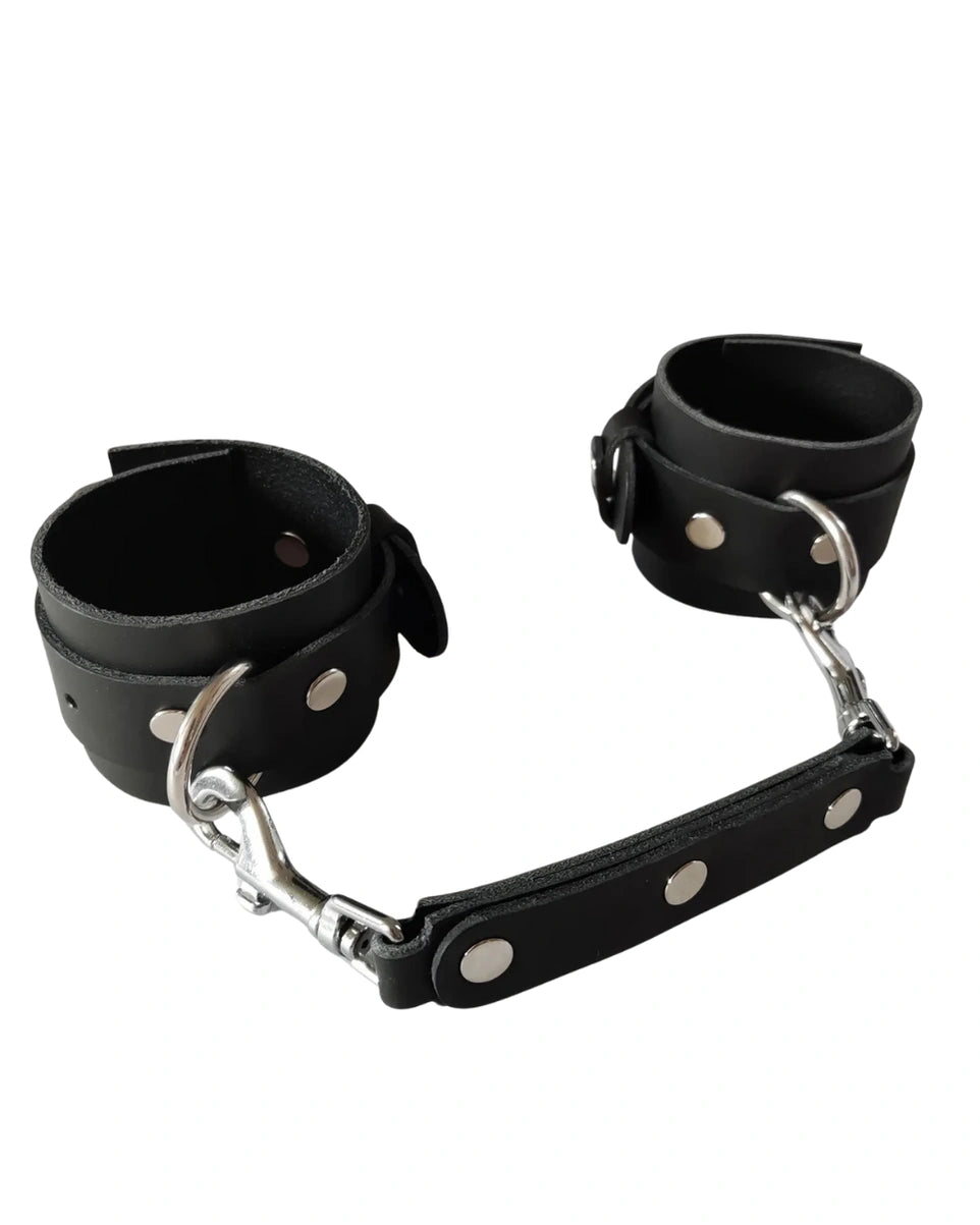 Two black faux leather cuffs with D-rings and short clip connector, product view