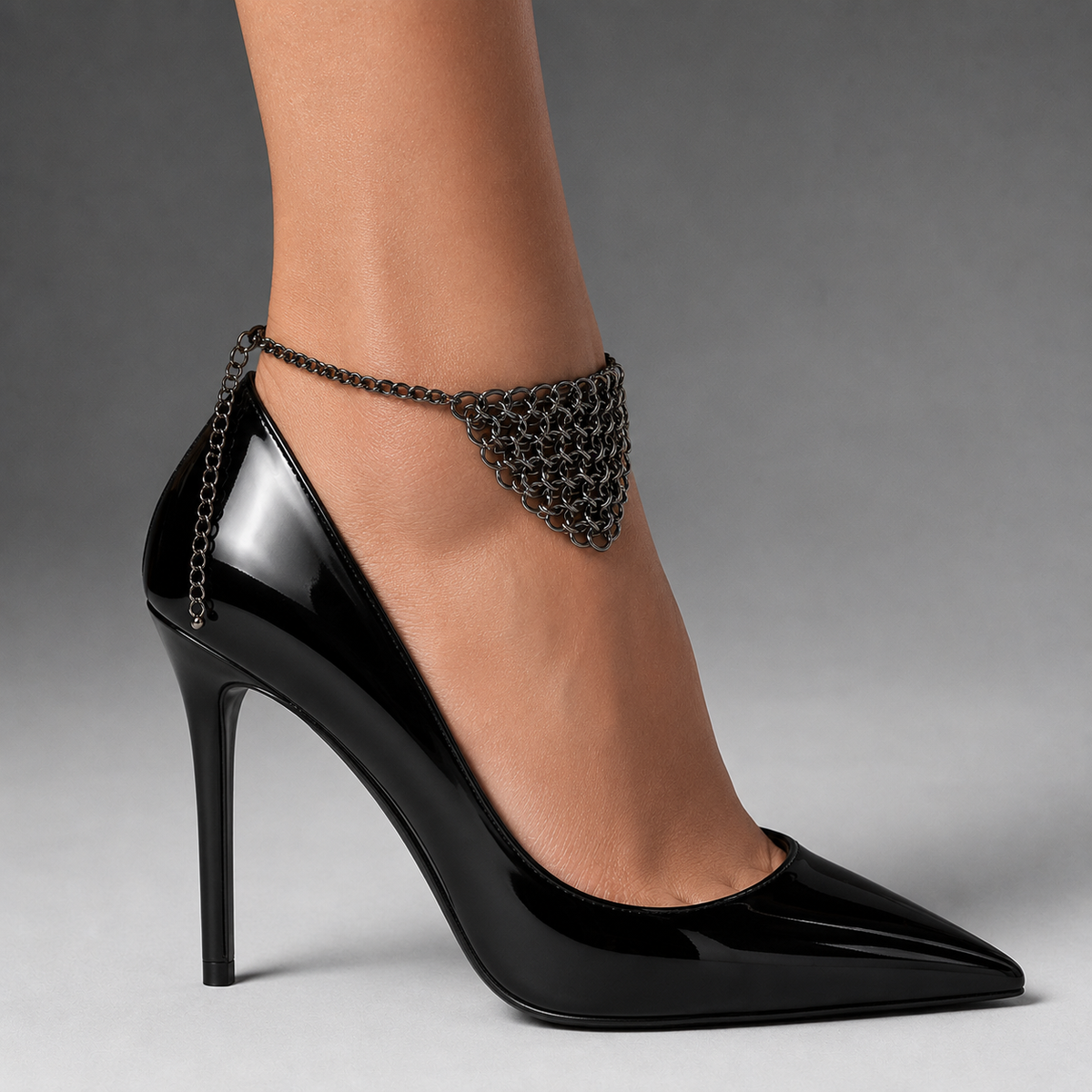 Chainmail anklet styled with black patent heels - woven metal armor foot panel, front view