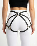 Black faux leather waist-to-thigh harness over white leggings, rear view